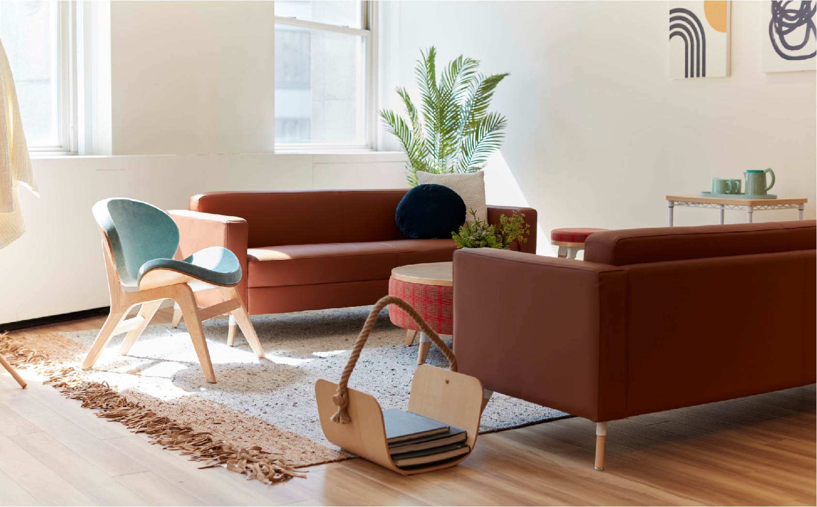 Image shows a lounge space with two brown sofas facing each other and stylish blue chair facing the couches
